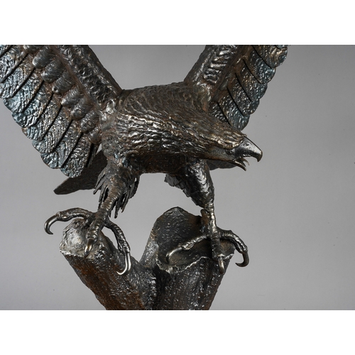 393 - Roy Whitmore :a patinated welded steel sculpture of an eagle with wings outstretched, perched on a l... 