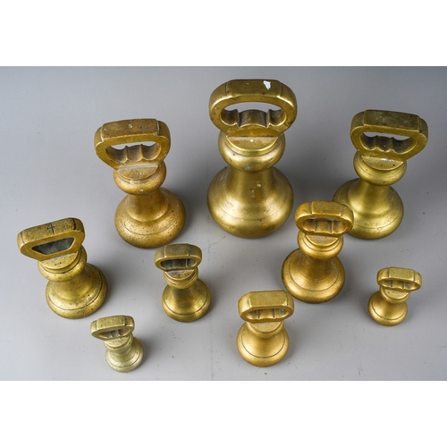 395 - A matched set of nine graduating brass bell weights, plain with weights to handles, one stamped Aver... 