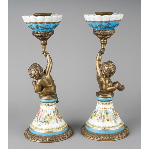 480 - A pair of decorative metal and earthenware candlesticks, each cast as a putto holding scones aloft, ... 