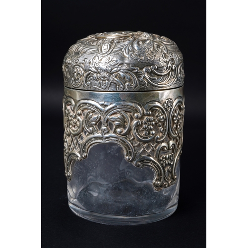 546 - A Victorian silver mounted cylindrical scent bottle, the hinged domed cover embossed with foliate sc... 