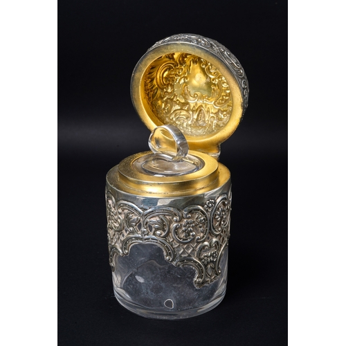 546 - A Victorian silver mounted cylindrical scent bottle, the hinged domed cover embossed with foliate sc... 