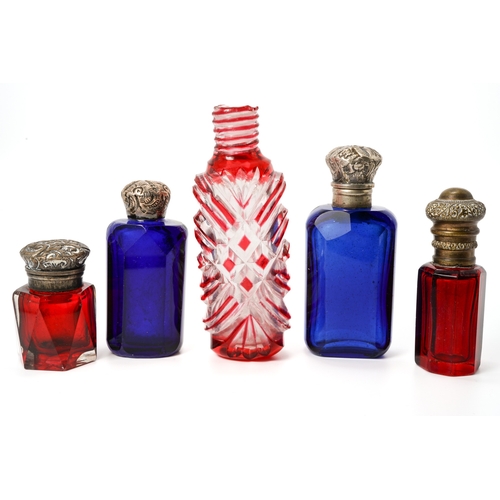 547 - A collection of five red and blue glass scent bottles, two with silver lids, two with base metal lid... 