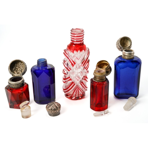 547 - A collection of five red and blue glass scent bottles, two with silver lids, two with base metal lid... 