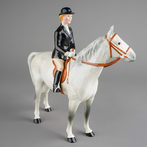 434 - A Beswick model of a Huntswoman on a dapple horse, she wears black jacket and bowler, stamped unders... 