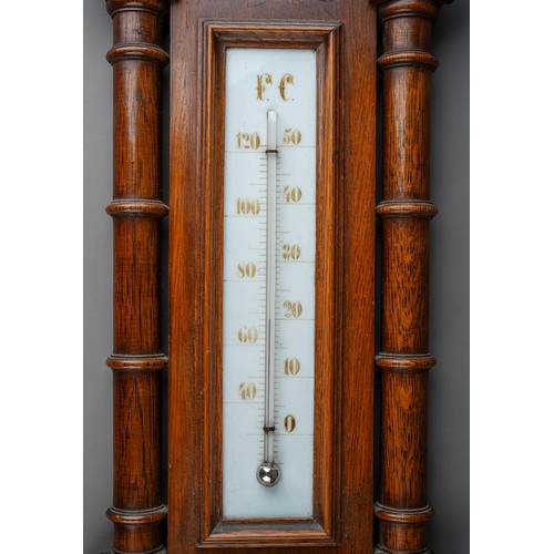 688 - A Victorian oak framed aneroid barometer, the carved case with pediment above column supports, the l... 