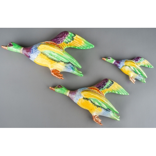 168 - A set of three graduated 1950s Beswick style flying ducks, vibrant colours in yellow, blue, green, m... 