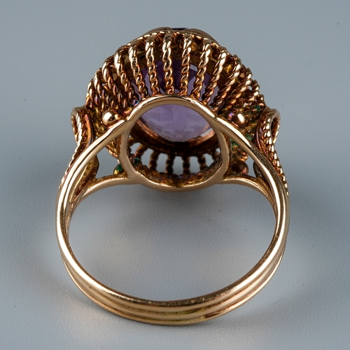 12 - A 9ct gold and amethyst dress ring, the large oval mixed-cut amethyst in rub-over settings, rope-twi... 