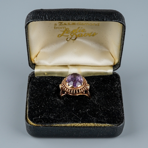 12 - A 9ct gold and amethyst dress ring, the large oval mixed-cut amethyst in rub-over settings, rope-twi... 