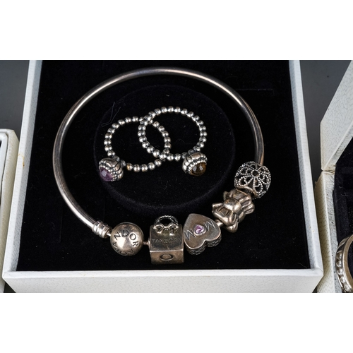 61 - A collection of silver jewellery, including two Pandora bracelets, rings, silver and CZ rings, gold-... 