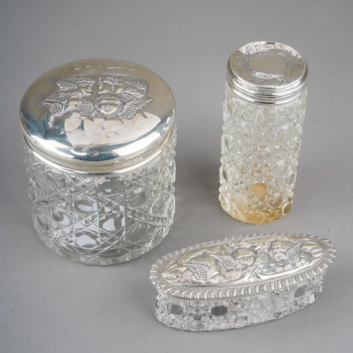 220 - Three early 20th Century silver mounted cut glass dressing table bottles / jars, two covers chased w... 