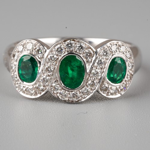 57 - An 18ct white gold emerald and diamond ring, set with three oval-cut emeralds within borders of roun... 