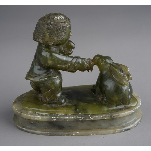 538 - A nephrite coloured carved figure of boy holding a rabbits on an oval plinth base