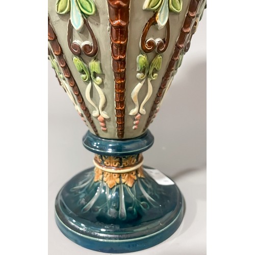 493 - A late 19th Century Majolica two handled vase, the sided with moulded strapwork with mask terminals,... 