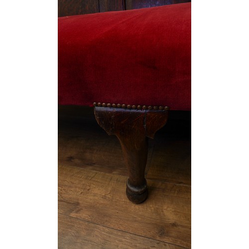 621 - A Victorian style stained oak carved settle, the back rest with geometric sections above red velvet ... 