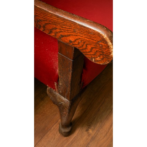 621 - A Victorian style stained oak carved settle, the back rest with geometric sections above red velvet ... 