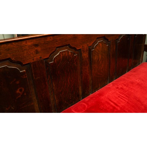 621 - A Victorian style stained oak carved settle, the back rest with geometric sections above red velvet ... 