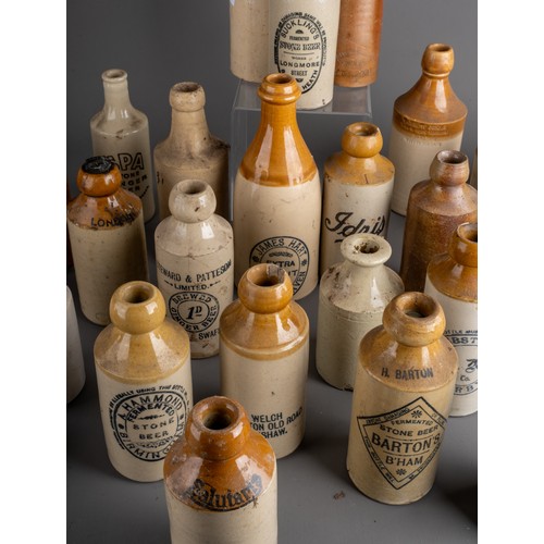 594 - Twenty-eight various stoneware beer and water bottles, some all cream, most with black transfer labe... 