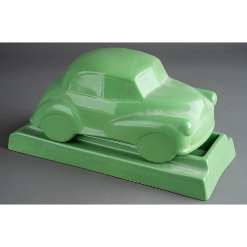 581 - A Dartmouth style desk model of ceramic green Morris Minor 1000 on separate stand with recess for pe... 