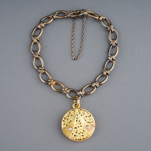 74 - A yellow gold bracelet and diamond locket, the fancy-link bracelet suspending a yellow circular lock... 