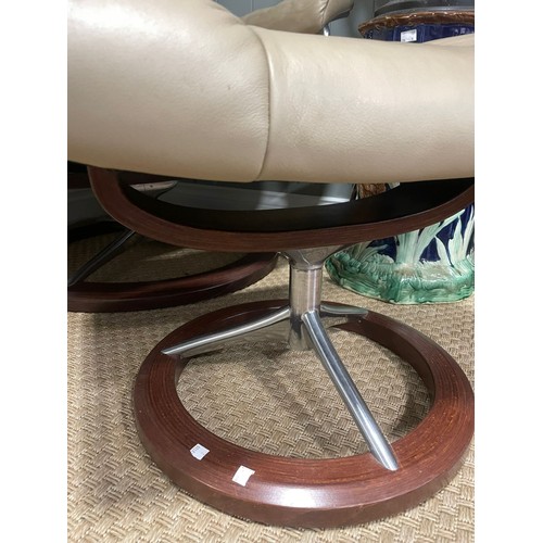 147 - A retro mid 20th century stressless reclining swivel armchair and foot stool. Having a rectangular c... 