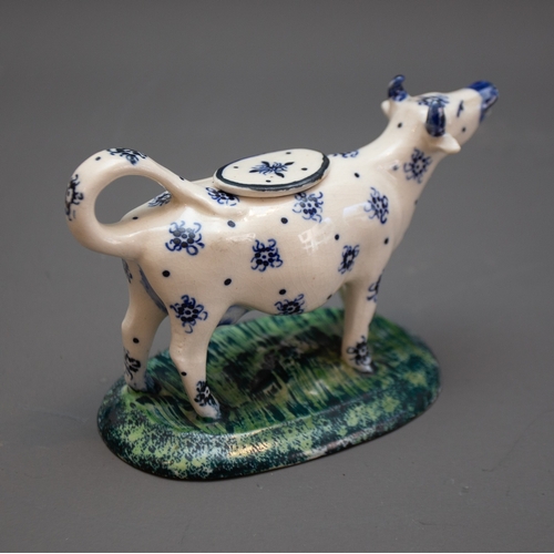 339 - An 18th Century style cow creamer, decorated with blue stylised flowers on oval base with striated a... 