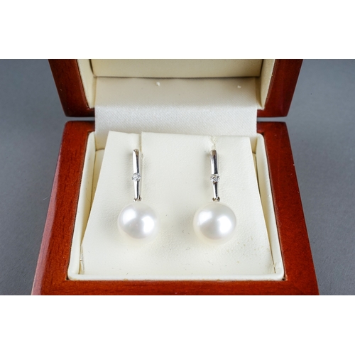 37 - A pair of 18k white gold diamond and pearl drop earrings, each set with a single round brilliant-cut... 