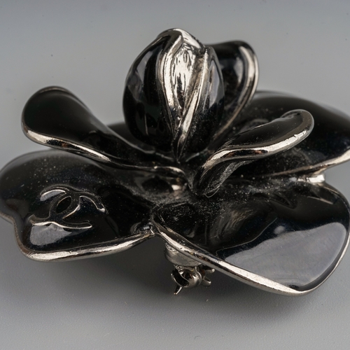 72 - Chanel - a black enamel flower brooch, interlocking C's, stamped to back 'Chanel Made in France 06',... 