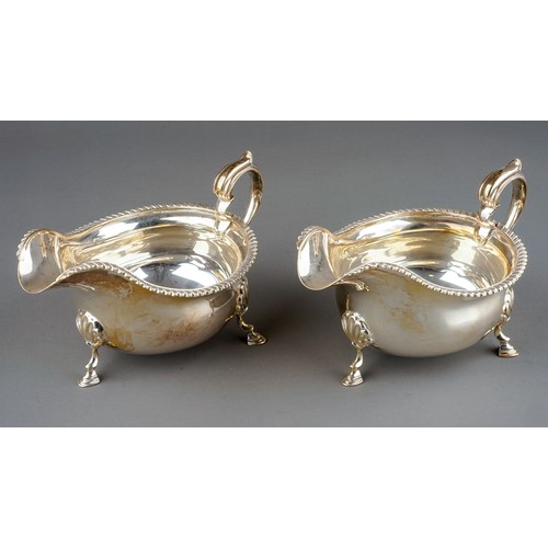 179 - A pair of Georgian style silver sauceboats, plain oval bodies with gadroon rims on three shell and h... 