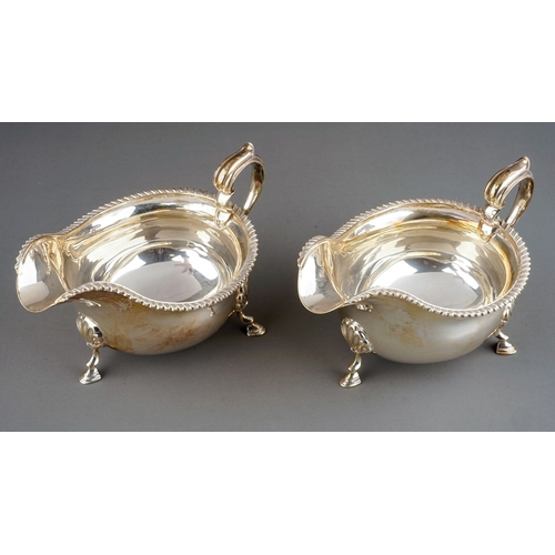 179 - A pair of Georgian style silver sauceboats, plain oval bodies with gadroon rims on three shell and h... 