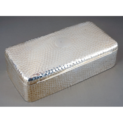 183 - An Arts & Crafts silver cigarette rectangular box, the entire hammered / planished with central vaca... 