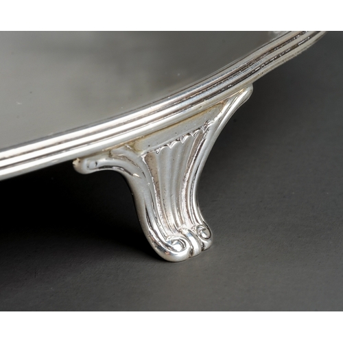 196 - A George III silver circular waiter, raised border, engraved with a crest, on three volute scroll fe... 