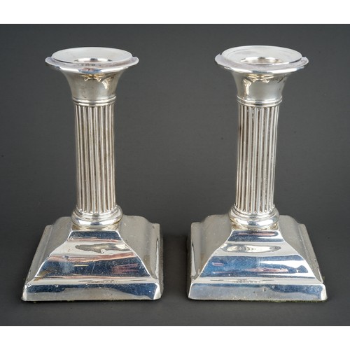 203 - A pair of Edwardian silver desk candlesticks, plain sconces above reeded columns on stepped supports... 