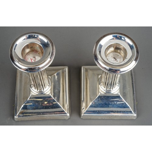 203 - A pair of Edwardian silver desk candlesticks, plain sconces above reeded columns on stepped supports... 