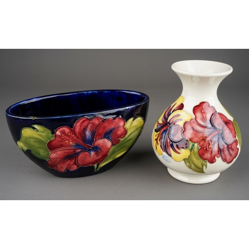 349 - Moorcroft bowl in Hibiscus pattern on a dark blue ground together with a vase on a cream background,... 