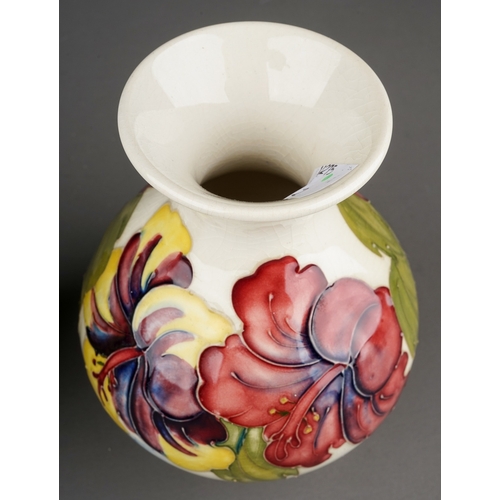 349 - Moorcroft bowl in Hibiscus pattern on a dark blue ground together with a vase on a cream background,... 