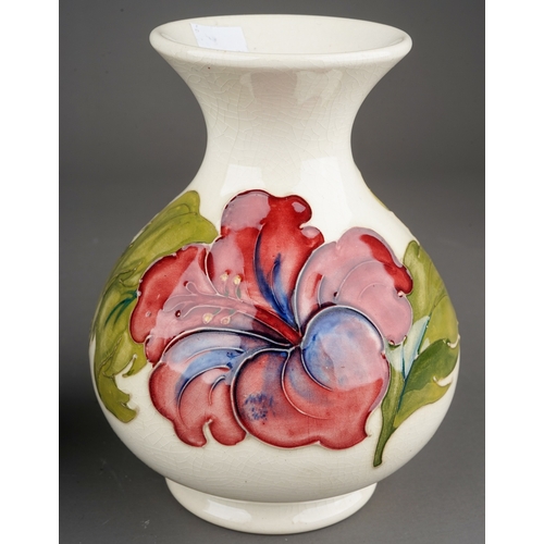 349 - Moorcroft bowl in Hibiscus pattern on a dark blue ground together with a vase on a cream background,... 