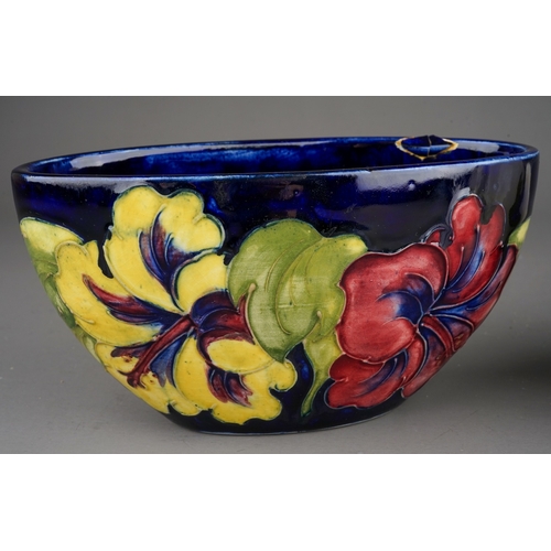 349 - Moorcroft bowl in Hibiscus pattern on a dark blue ground together with a vase on a cream background,... 