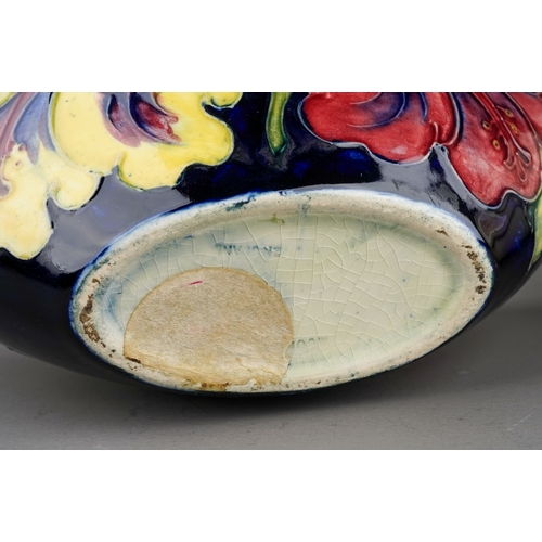 349 - Moorcroft bowl in Hibiscus pattern on a dark blue ground together with a vase on a cream background,... 