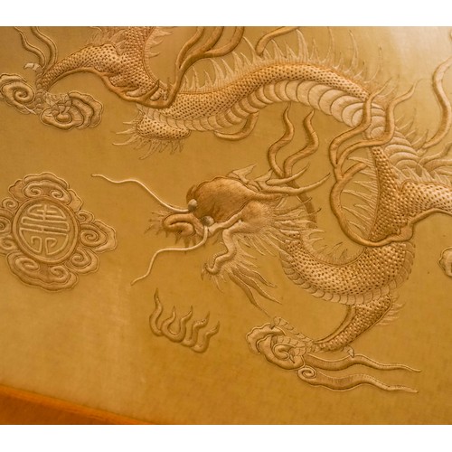 478 - A Chinese embroidered cream silk panel depicting a four claw dragon, clouds to the skyline and sun t... 