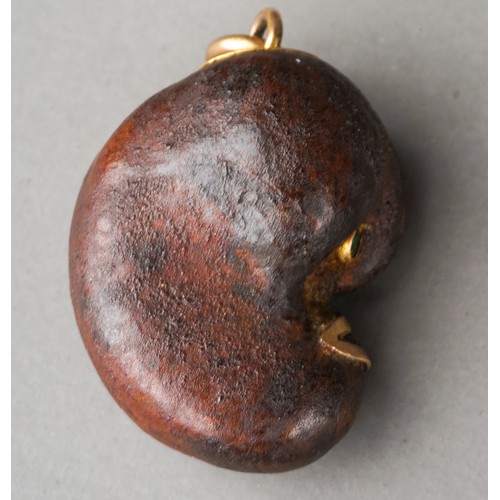 567 - Tagua nut ? Lucky bean charm with green stone eyes and high carat gold mounts, circa 1900