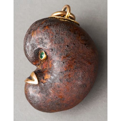 567 - Tagua nut ? Lucky bean charm with green stone eyes and high carat gold mounts, circa 1900