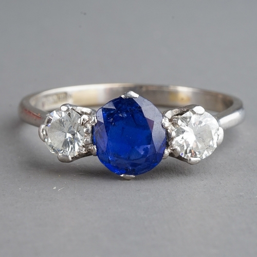 28 - A sapphire and diamond three-stone ring, set with a mixed-cut sapphire flanked by two round brillian... 