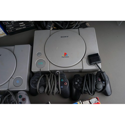 106 - Two Sony PlayStation 1s and a Sony Playstation 2 game consoles with five controllers together with a... 