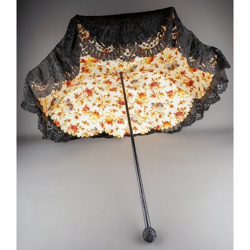 573 - A late Victorian black lace parasol with rose chintz fabric interior lining, on a carved ebonised sh... 