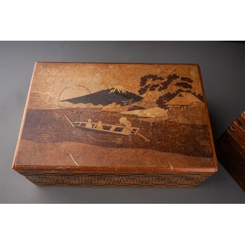 577 - An early 20th century Japanese inlaid puzzle box, decorated with figures in a boat, birds in trees a... 