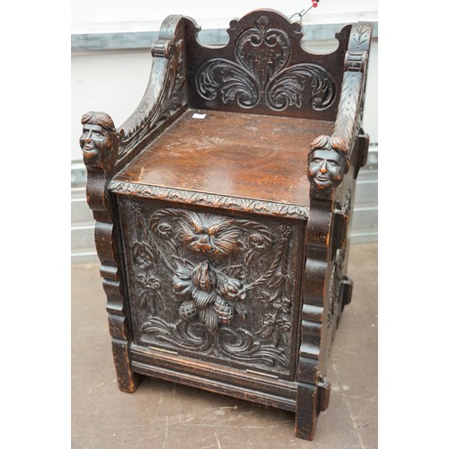 598 - A Victorian Gothic oak combination hall seat and coal skuttle, the fall front carved with Lion`s hea... 