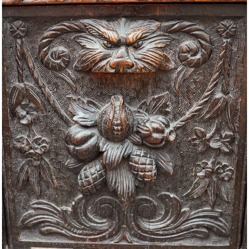 598 - A Victorian Gothic oak combination hall seat and coal skuttle, the fall front carved with Lion`s hea... 