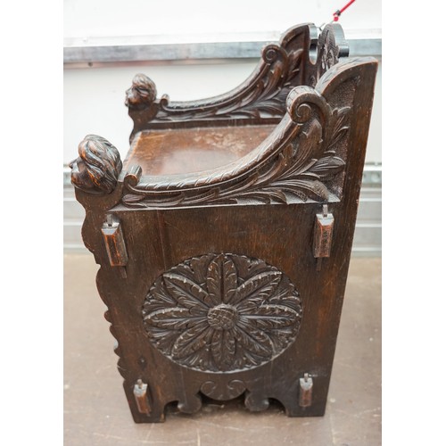 598 - A Victorian Gothic oak combination hall seat and coal skuttle, the fall front carved with Lion`s hea... 