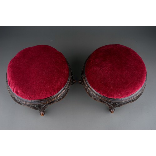 619 - A pair of late Victorian circular walnut footstools, red velvet upholstered inset tops, foliate carv... 