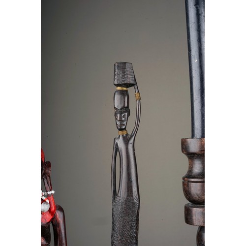 131A - A collection of seven late 20th century tribal figures, including a pair of candlesticks carved with... 